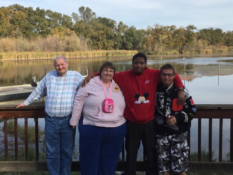 La Cruz clients standing together on a creek bridge smiling and enjoying the afternoon.